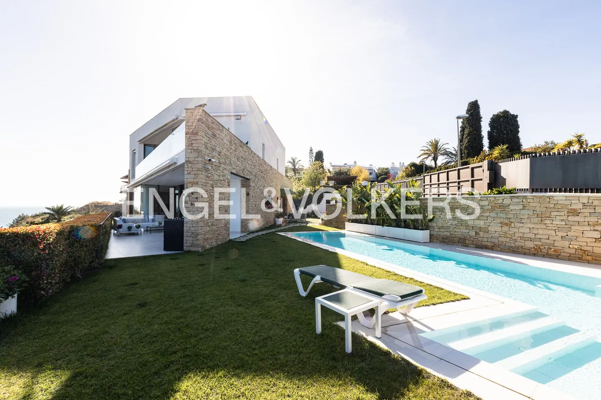 Piscina exterior junto a una casa en Sant Pol de Mar con fachada de piedra natural y jardín.