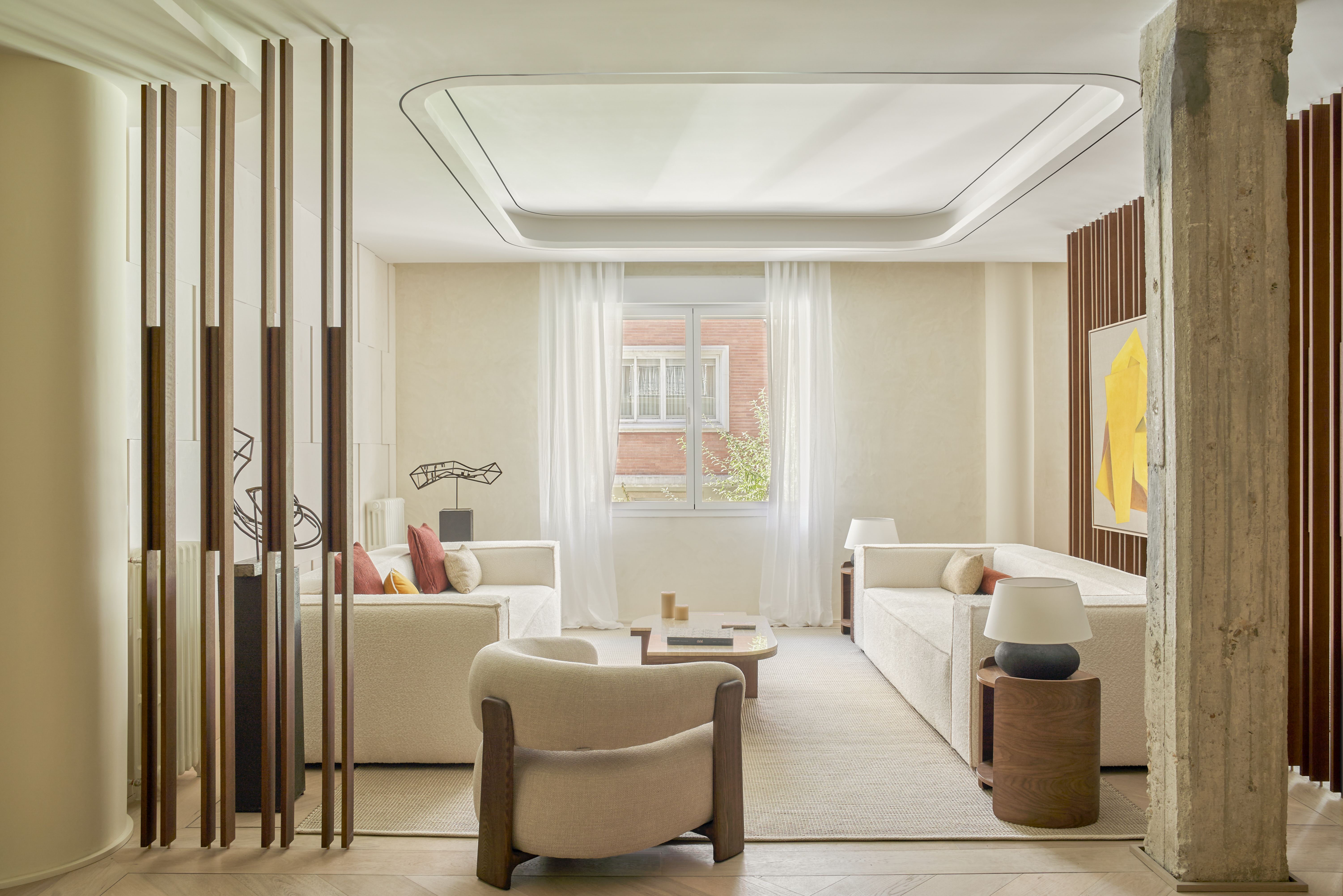 Salón abierto con celosías de madera, techo curvo con iluminación indirecta y suelo continuo, un ejemplo de decoración para una casa más elegante.
