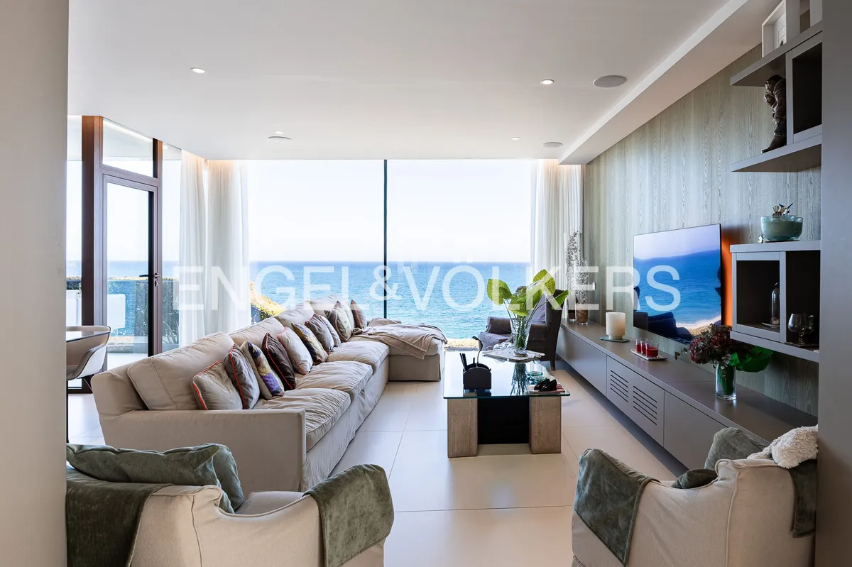 Salón de una casa en Sant Pol de Mar con grandes ventanales y vistas panorámicas al Mediterráneo.