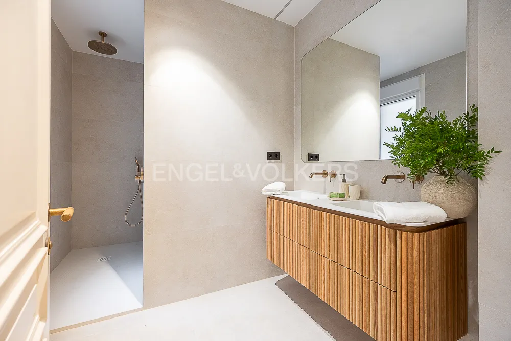 Baño con ducha a ras de suelo y mueble suspendido de madera en una casa junto a El Retiro en Madrid