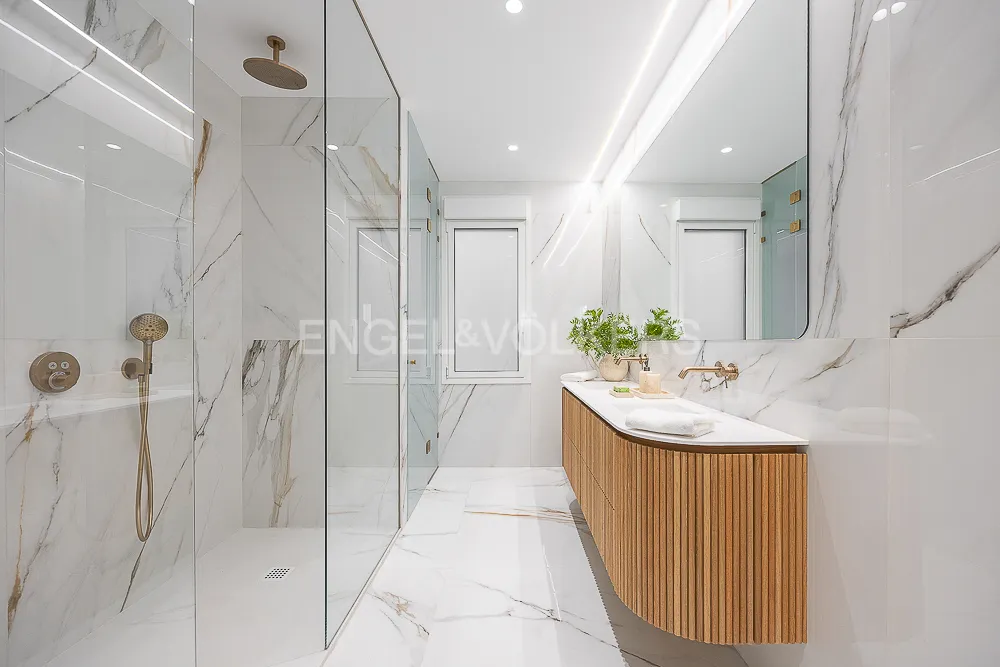 Baño de la suite principal con revestimientos efecto mármol y ducha a ras de suelo en una casa junto a El Retiro