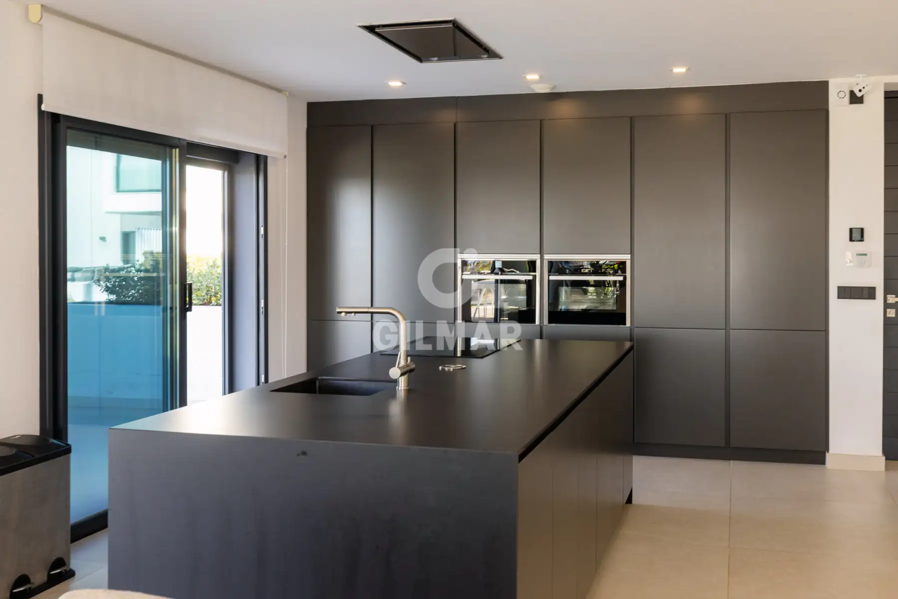 Cocina de diseño con gran isla central y acabados en negro mate en una casa frente al mar en Estepona