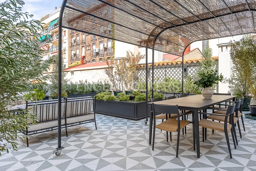 Comedor exterior bajo pérgola en una terraza privada de 119 m² junto a El Retiro en Madrid