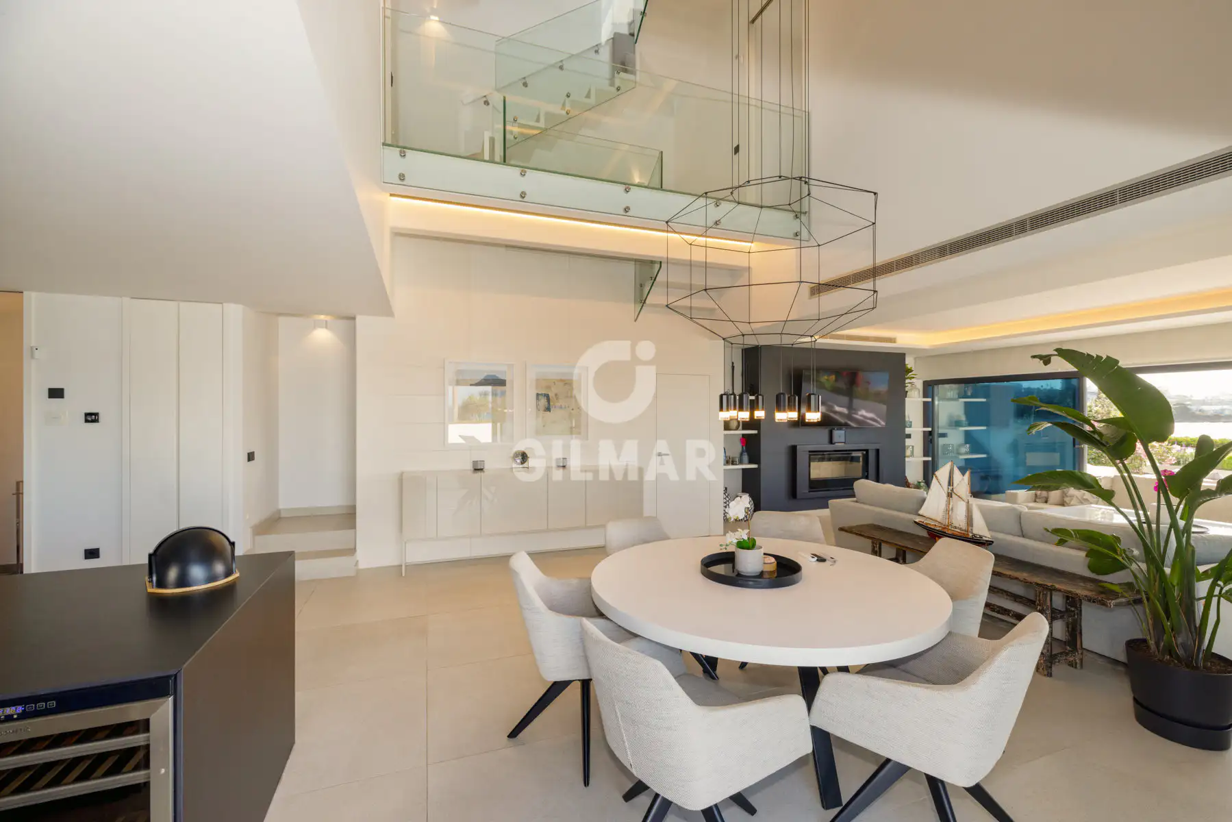 Mesa de comedor redonda bajo una lámpara escultórica en una vivienda de lujo frente al mar en Estepona