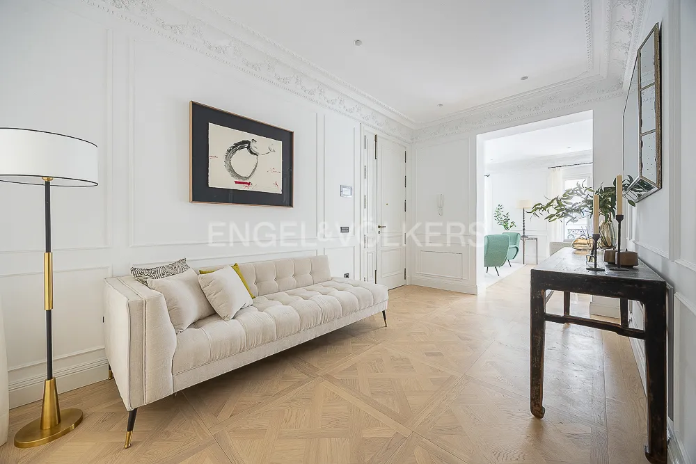 Distribuidor de una casa con terraza junto a El Retiro en Recoletos, Madrid, con molduras clásicas, suelo geométrico de madera y mobiliario elegante