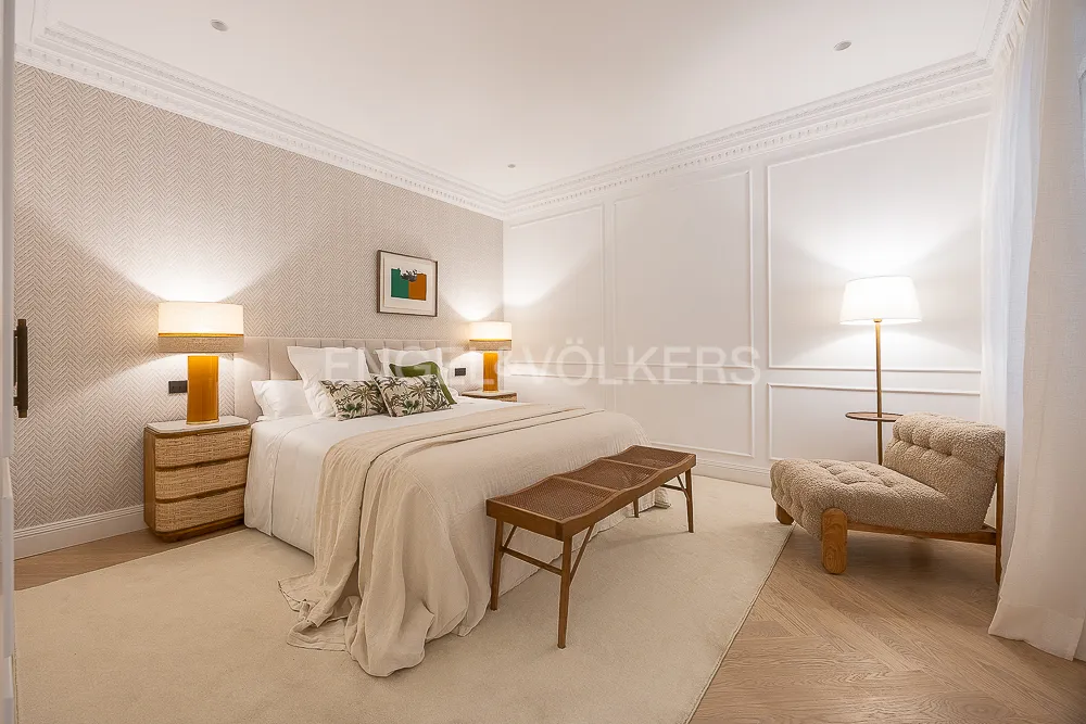 Dormitorio principal de una casa con terraza junto a El Retiro con rincón de lectura, molduras clásicas y decoración en tonos neutros