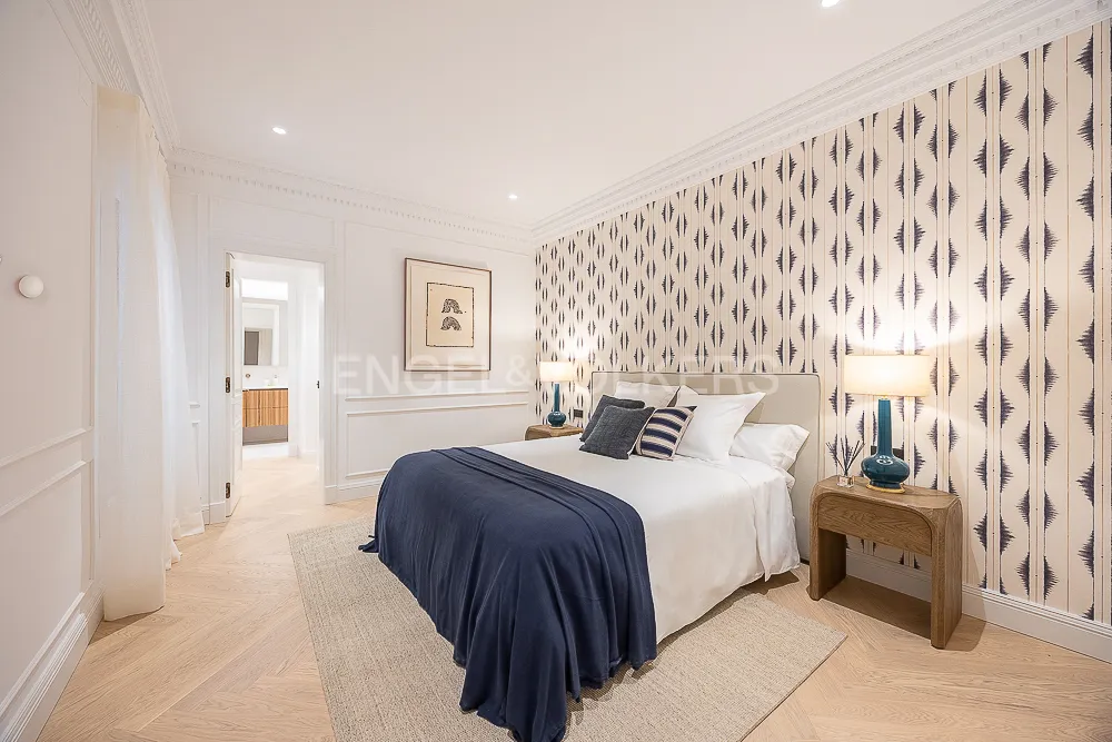 Dormitorio tipo suite de una casa con terraza junto a El Retiro con papel pintado decorativo, molduras clásicas y textiles en azul